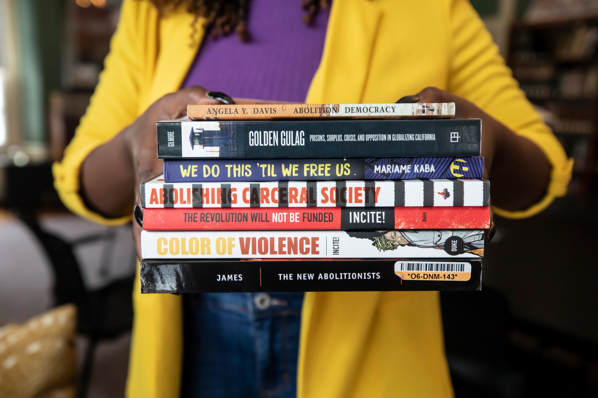 A woman holds a stack of books